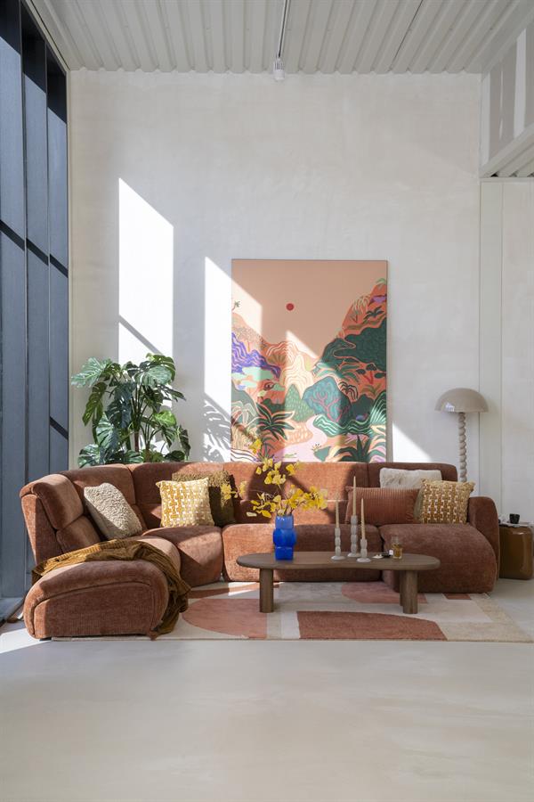 Gezellige woonkamer met een grote, comfortabele bank, kleurrijke kussens, een houten salontafel en een opvallend kunstwerk aan de muur, ingericht met Mokana meubelen.