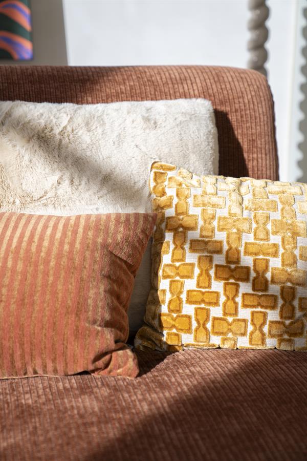 Gezellige bank met drie kussens in verschillende texturen en kleuren, perfect voor een moderne woonkamer.