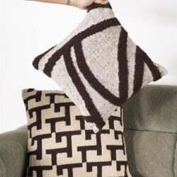 Twee stijlvolle sierkussens met geometrische patronen, geplaatst op een groene bank, perfect voor moderne woonkamer decoratie en comfort.