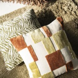 Drie stijlvolle decoratieve kussens met verschillende patronen en texturen, geplaatst op een zachte tapijt, ideaal voor woonkamer of slaapkamer.