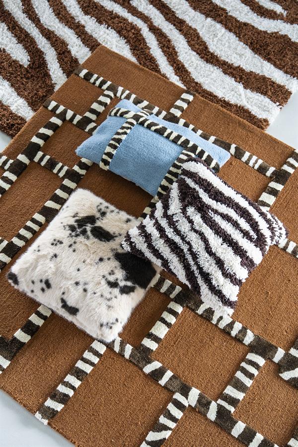 Stijlvol dierenprint vloerkleed met zebra- en luipaardmotieven, gecombineerd met kleurrijke kussens voor een trendy woonkamer uitstraling. Perfect voor een warme en gezellige sfeer.