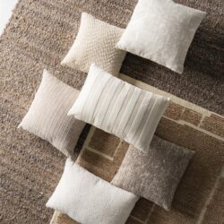 Diverse decoratieve kussens en tapijten in neutrale tinten, perfect voor het inrichten van een gezellige woonkamer of slaapkamer.
