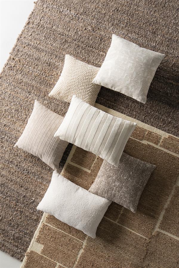 Set van diverse decoratieve kussens en tapijten in neutrale tinten, ideaal voor woonkamer en slaapkamer, met verschillende texturen en patronen.