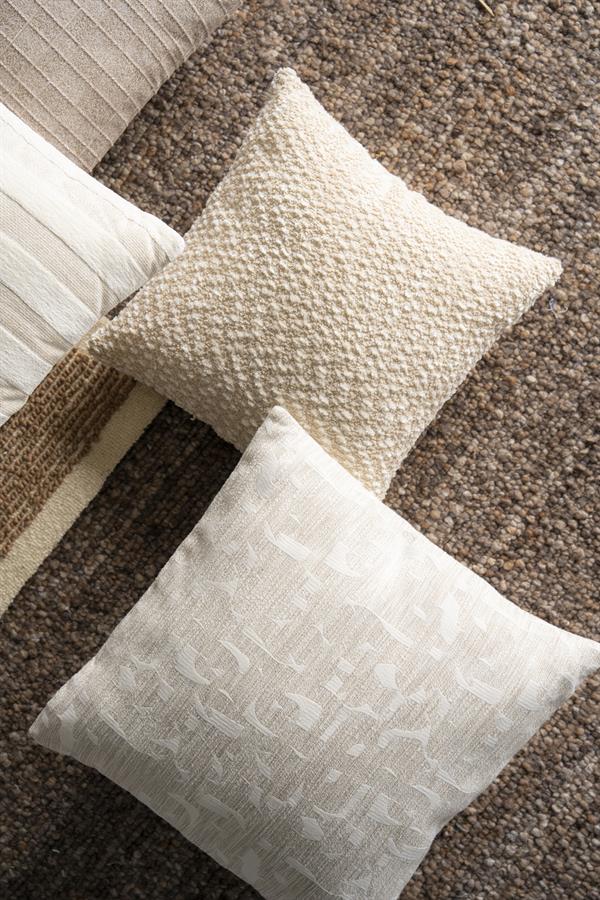 Twee decoratieve kussens op een tapijt in een woonkamer, met een beige en een witte kussen, perfect voor een gezellige en stijlvolle zithoek.