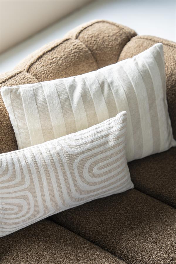 Kussen met beige en witte strepen en patronen, geplaatst op een comfortabele bank. Perfect voor een stijlvolle en gezellige woonkamer.