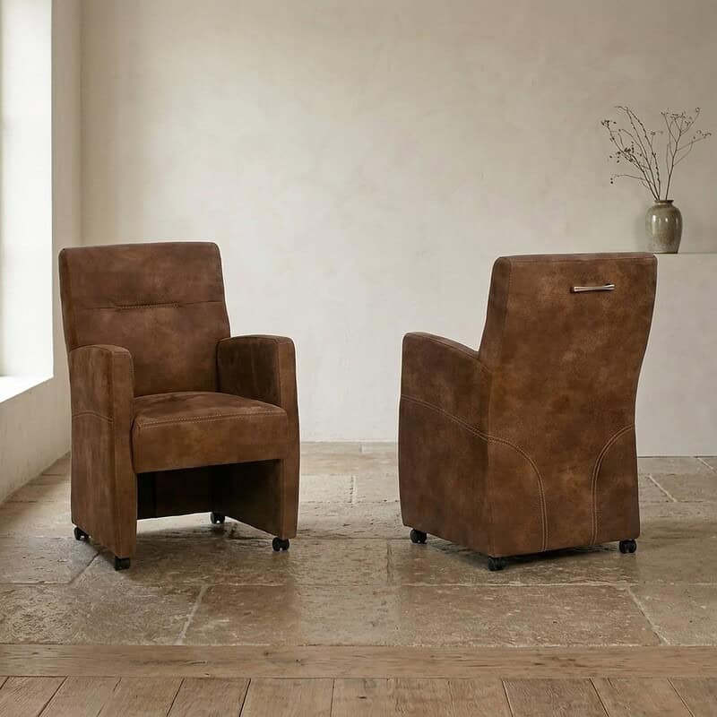 Twee stijlvolle houten fauteuils in een minimalistisch interieur met een lichte muur en een vaas met takken op de achtergrond, perfect voor een moderne woonkamer of lounge.