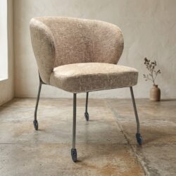 Comfortabele beige fauteuil met metalen poten en wieltjes, perfect voor moderne en vintage interieurs.