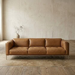 Luxe leren bank in een minimalistisch interieur met een lichte, neutrale achtergrond en houten vloer, perfect voor moderne woonruimtes en stijlvolle woonkamerinrichting.