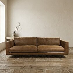 Luxe leren bank in een modern, minimalistisch interieur met natuurlijke tinten en houten vloer, perfect voor een stijlvolle woonkamer.