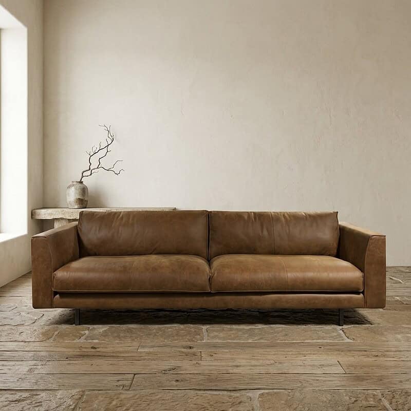 Luxe leren bank in een modern, minimalistisch interieur met natuurlijke tinten en houten vloer, perfect voor een stijlvolle woonkamer.