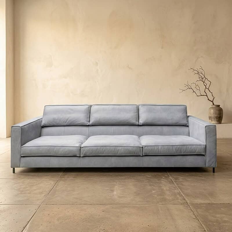 Moderne grijze bank in een minimalistische woonkamer, perfect voor stijlvolle en comfortabele zitplekken. Ideaal voor een eigentijdse inrichting met focus op comfort en design.