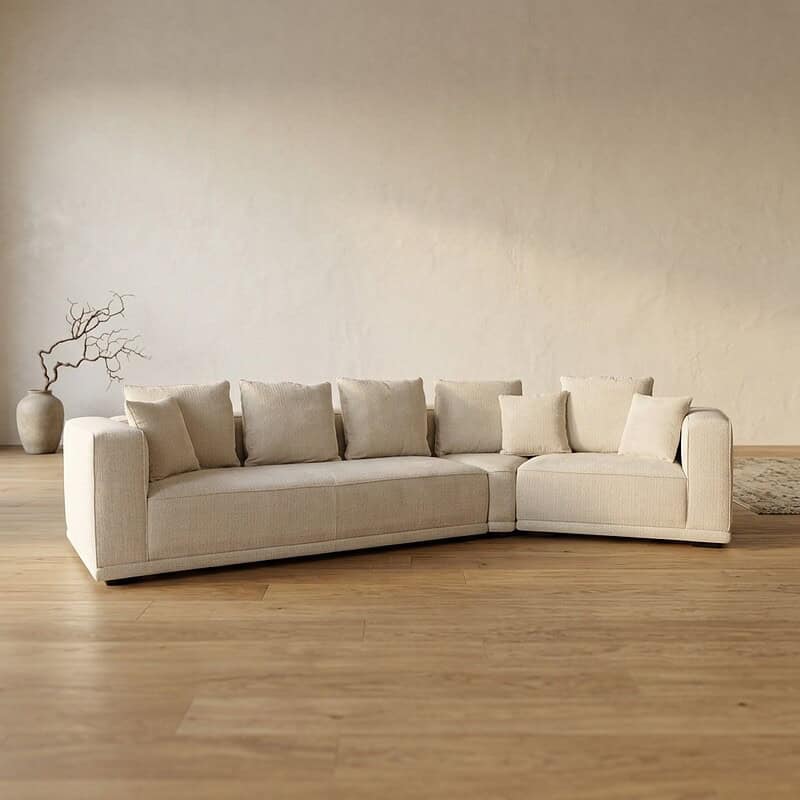 Elegante hoekbank in een minimalistisch woonkamer met natuurlijke kleuren en houten vloer, perfect voor stijlvolle en comfortabele zithoeken.