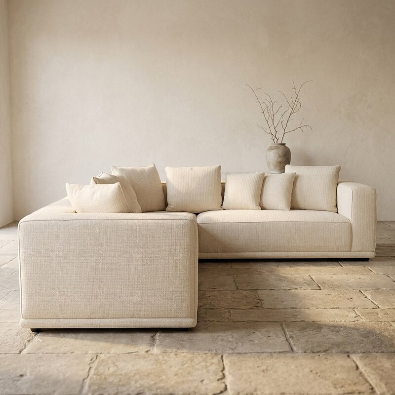Moderne beige loungebank met kussens in een minimalistisch interieur, perfect voor een stijlvolle woonkamer.