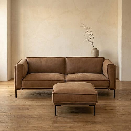 Luxuriöses Ledersofa mit Fußhocker in einem minimalistischen Wohnzimmer, perfekt für stilvolle und bequeme Sitzecken.