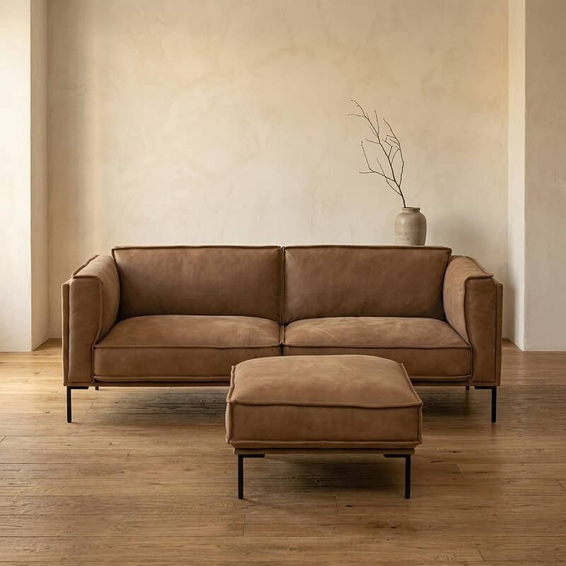 Luxe leren bank met voetenbank in een minimalistisch woonkamerinterieur, perfect voor stijlvolle en comfortabele zithoeken.