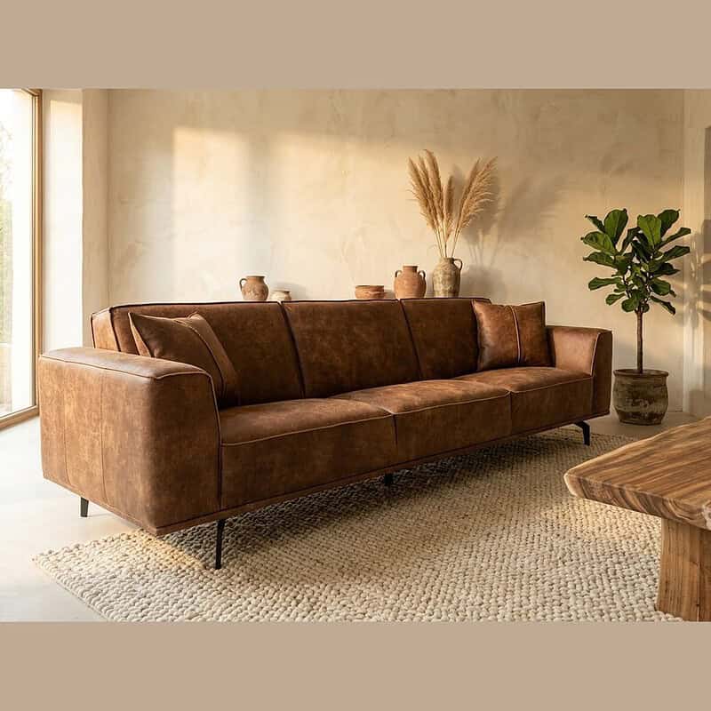 Bruine leren bank, modern interieur, natuurlijke decoratie, grote ramen, woonkamer, stijlvolle meubels, comfortabele zitplek, design bank, wooninrichting, Mokana Meubelen.