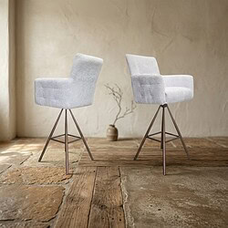 Twee moderne witte eetkamerstoelen met metalen poten op een houten vloer, geschikt voor een eigentijdse eetkamer of woonkamer.