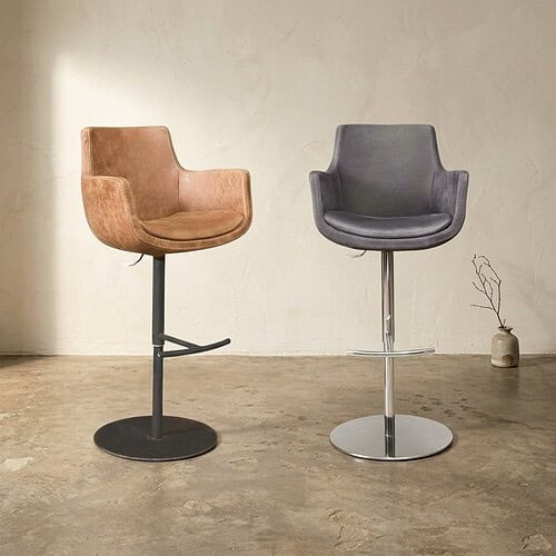 Twee moderne barkrukken, een met houten bekleding en de andere met leren bekleding, geplaatst in een minimalistische interieursetting. Perfect voor eetkamers of bars.