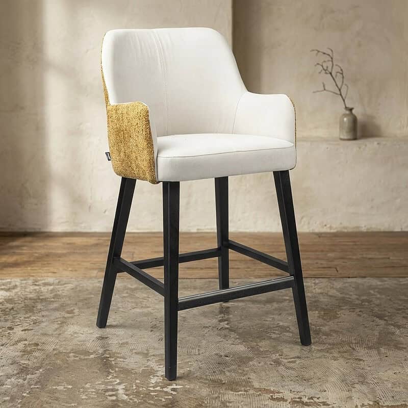 Moderne houten barkruk met witte bekleding, gouden armleuningen en zwarte poten, geschikt voor keukeneilanden en bars.