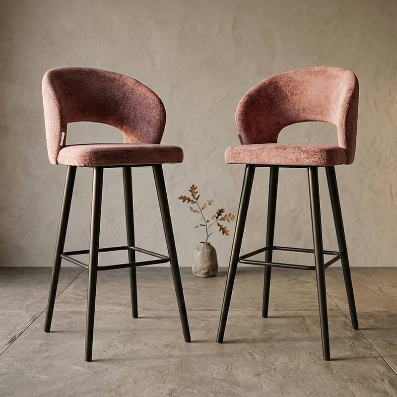 Twee moderne velvet barkrukken met zwarte houten poten en een zachte roze bekleding, ideaal voor een stijlvolle keuken of bar.