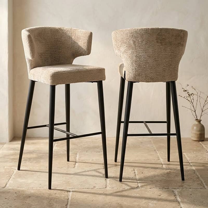 Twee moderne barkrukken met beige stoffen bekleding en zwarte houten poten, ideaal voor een stijlvolle keuken of bar. Perfect voor comfort en design.