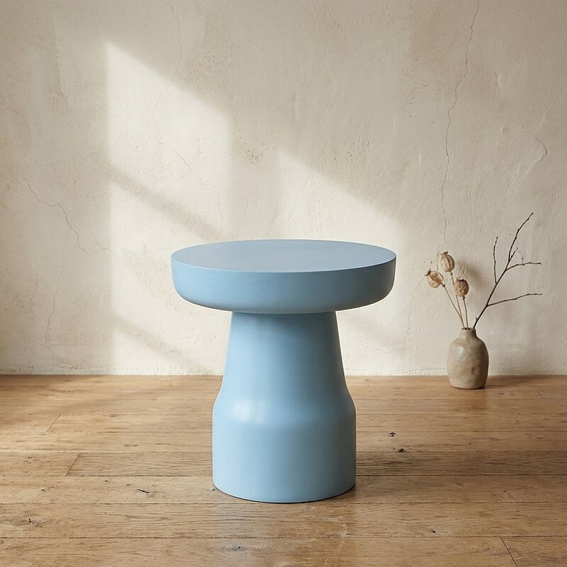 Moderne blauwe bijzettafel met ronde bovenkant en unieke sculpturale basis, perfect voor een eigentijdse woonkamer of slaapkamer.