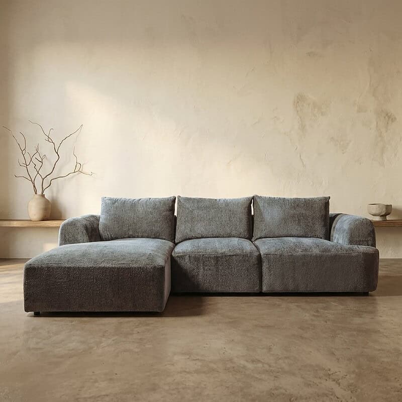 Moderne grijze hoekbank in een minimalistisch interieur, perfect voor een stijlvolle woonkamer. Gemaakt van hoogwaardig materiaal, biedt comfort en elegantie.
