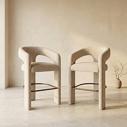 Zwei moderne Sessel mit weicher Polsterung und Armlehnen aus Holz, platziert in einem minimalistischen Interieur. Perfekt für eine stilvolle und gemütliche Sitzecke.