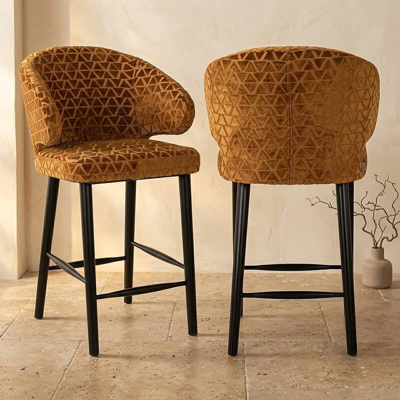 Twee moderne stoelen met geometrisch patroon in bruin fluweel en zwarte poten, geschikt voor woonkamer of eetkamer.