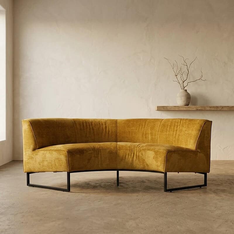 Elegante gele velvet bank van Mokana Meubelen in een minimalistisch interieur met een neutrale muur en een decoratieve vaas op een plank. Perfect voor een stijlvolle woonkamer.