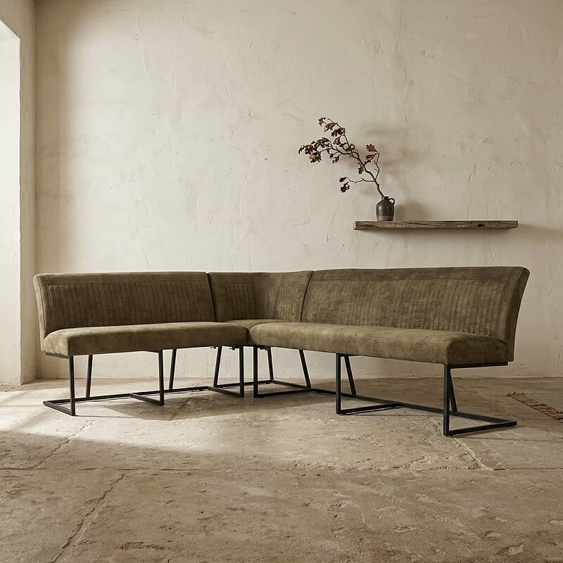 Moderne hoekbank in groen fluweel met zwart metalen poten, perfect voor een stijlvolle woonkamer.