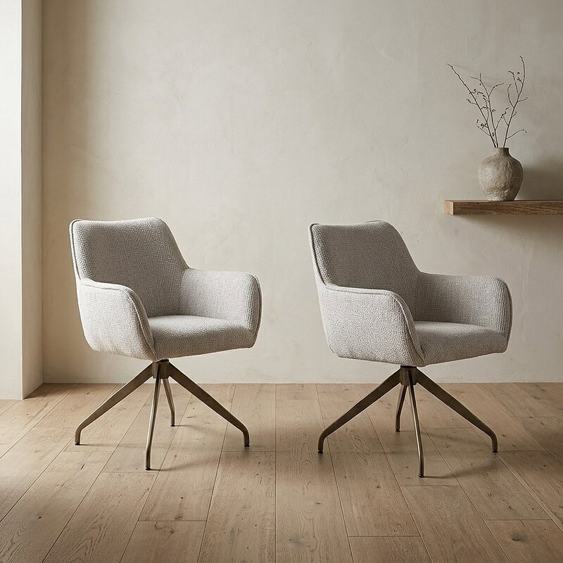 Twee moderne fauteuils met lichte stoffering en houten poten in een minimalistische interieursetting, perfect voor een stijlvolle woonkamer of kantoorruimte.