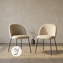 Zwei beige Sessel mit schwarzen Metallbeinen im minimalistischen Design, platziert in einem hellen Wohnzimmer mit einer dekorativen Vase und Zweigen.