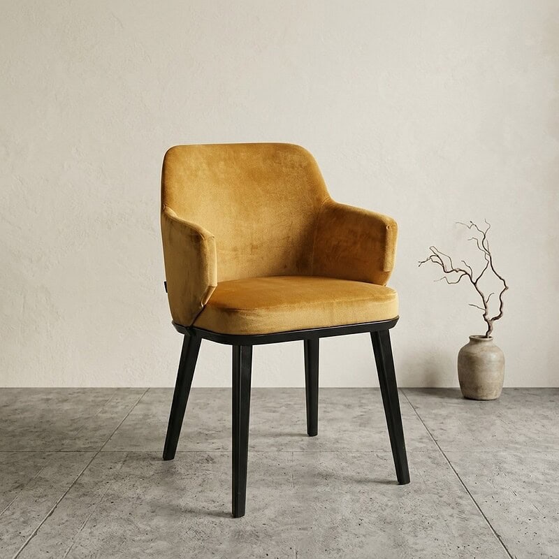 Elegante Mokana fauteuil met gele velvet bekleding en zwarte houten poten, perfect voor modern interieur en comfortabele zitervaring.