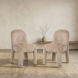 Zachte stoffen stoelen in een minimalistisch interieur met een eenvoudige houten plank en een decoratieve vaas met takken, perfect voor moderne woonruimtes.