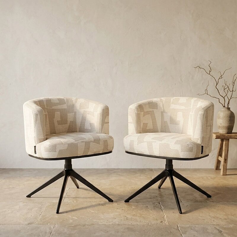Twee moderne zitstoelen met beige en witte geometrische stoffen bekleding en zwarte houten poten, geplaatst in een minimalistische interieursetting.