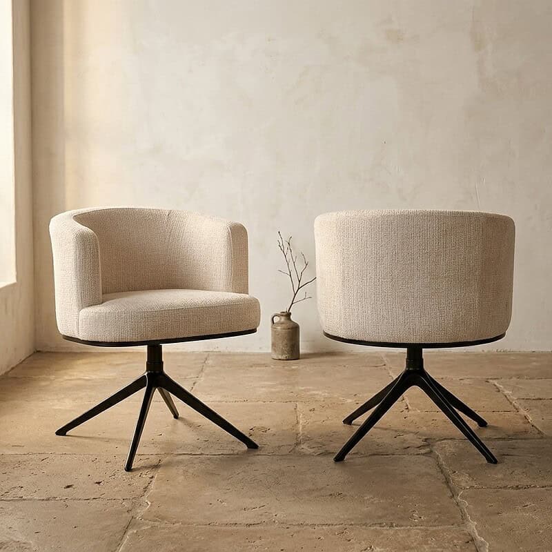 Twee beige lounge stoelen met zwarte metalen pootjes in een minimalistische interieur setting, perfect voor een stijlvolle en comfortabele zithoek.
