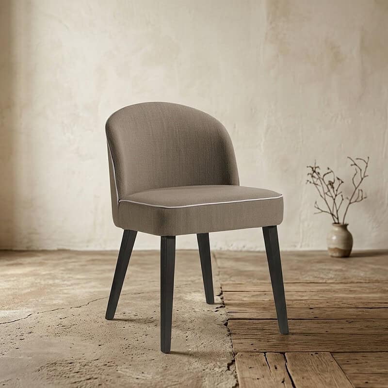 Elegante Mokana meubelstoel met zachte bekleding en zwarte houten poten, perfect voor moderne woonruimtes en eetkamers.