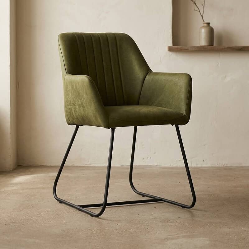 Elegante groene velvet eetkamerstoel met slanke zwarte metalen poten, perfect voor een stijlvolle en comfortabele eetruimte of kantoor.
