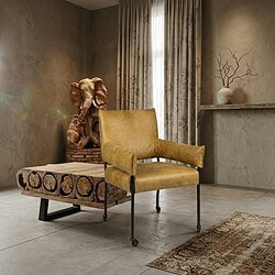 Elegante vintage houten fauteuil met zachte gele bekleding, geplaatst in een modern interieur met natuurlijke decoratie en grote ramen. Perfect voor stijlvolle woonruimtes en comfortabele zithoeken.