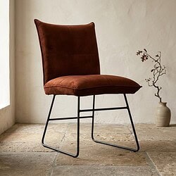Moderne bruine fluwelen stoel met zwart metalen frame, perfect voor een stijlvolle woonkamer of kantoor, ontworpen door Mokana Meubelen.