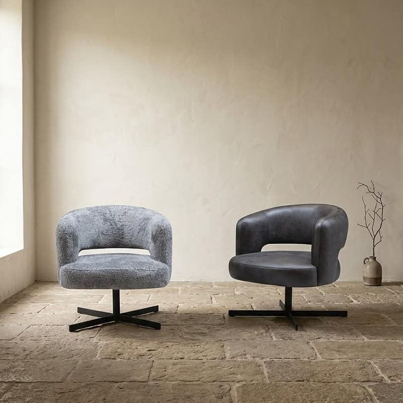Twee stijlvolle fauteuils in zwart en grijs leer, perfect voor een modern interieur, geplaatst in een minimalistische kamer met natuurlijke lichtinval.