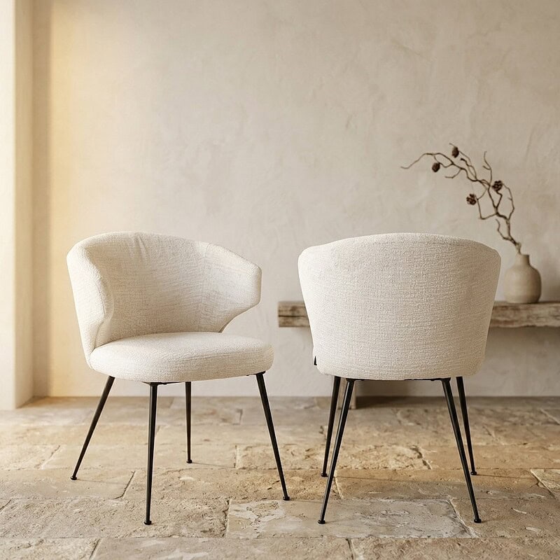 Moderne witte fauteuils met zachte bekleding en slanke zwarte poten, perfect voor een stijlvolle woonkamer of lounge.