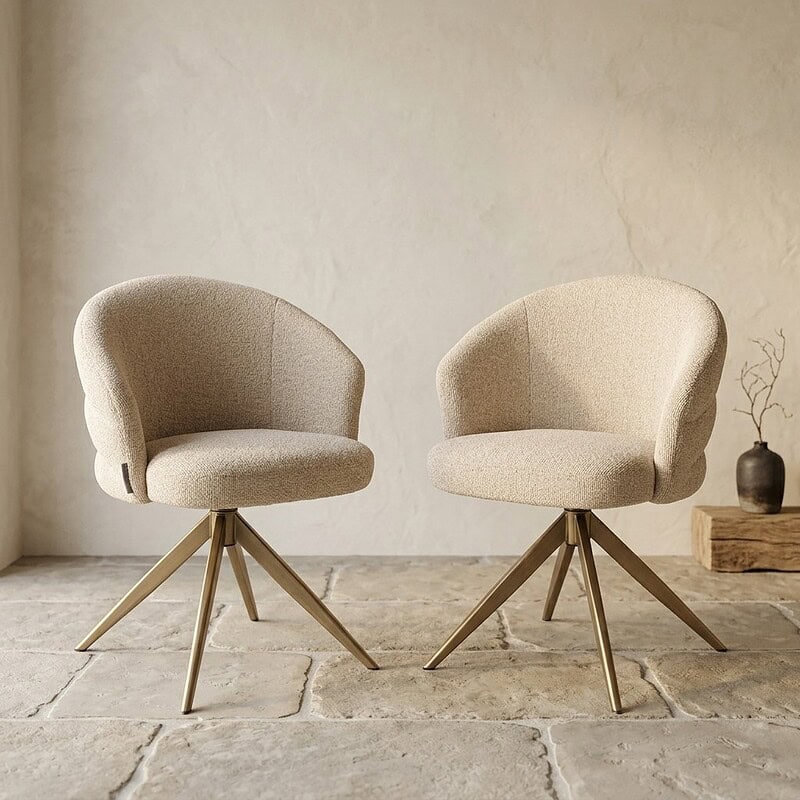 Twee moderne houten fauteuils met zachte, beige bekleding en ronde armleuningen, geplaatst op een stenen vloer in een minimalistische interieursetting.