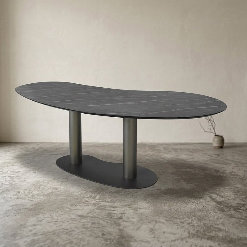 Zwarte houten eettafel met een uniek ovaal ontwerp en metalen poten, perfect voor moderne eetkamers. Ontdek duurzame en stijlvolle meubelstukken bij Mokana Meubelen.