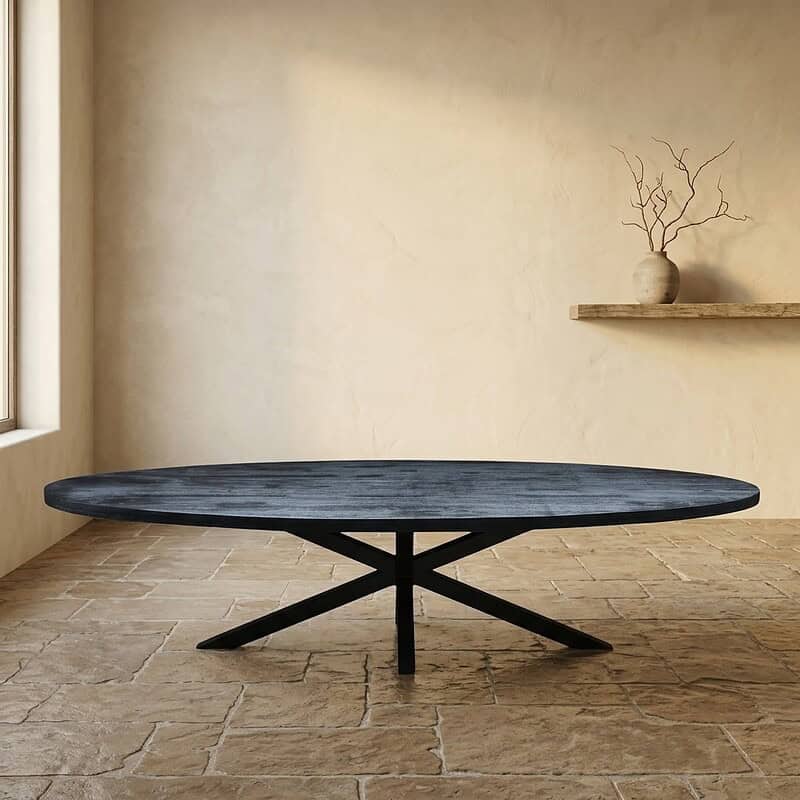 Moderne massief houten eettafel met zwart onderstel in minimalistische woonkamer, natuurlijke lichtinval, rustieke vloer, decoratieve takken in vaas op muurplank.