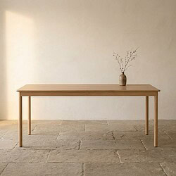 Strakke eettafel van massief hout met minimalistische vaas en takken, perfect voor een moderne en natuurlijke interieurstijl.