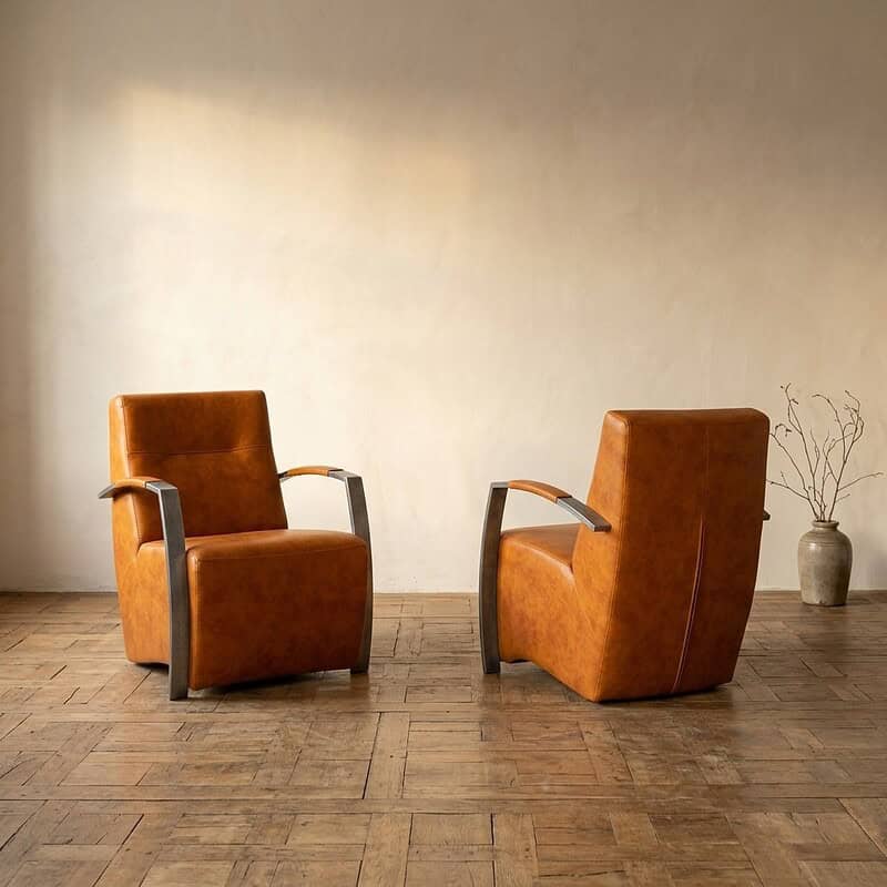 Zwei Vintage-Ledersessel mit Holzarmlehnen in einer minimalistischen Einrichtung – perfekt für ein stilvolles Wohnzimmer oder eine Lounge.