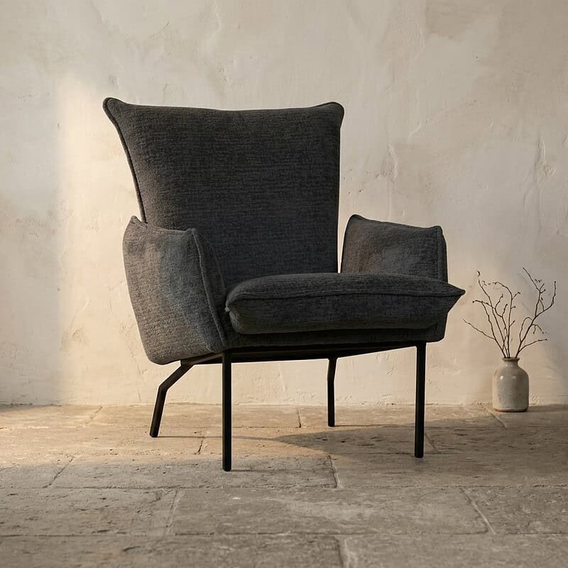 Luxe moderne fauteuil in donkergrijs stof met armleuningen en slanke metalen poten, perfect voor een stijlvolle woonkamer of kantoorruimte.