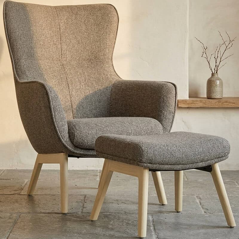 Moderne hoge fauteuil met bijpassende ottoman, perfect voor een stijlvolle en comfortabele zithoek in huis. Gemaakt van hoogwaardige materialen met een Scandinavisch design.